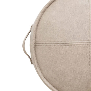 Close-up of a round beige leather-look stool showing stitched paneling and a small loop handle.