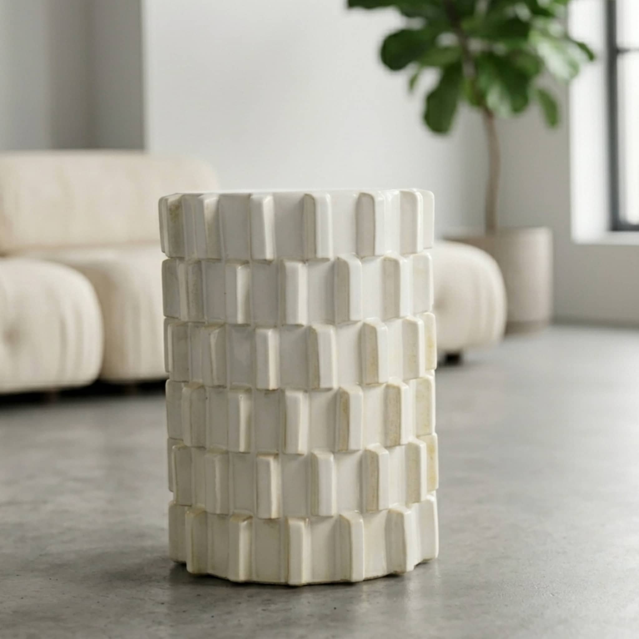 Off-white ceramic stool with raised block pattern styled in a living room setting
