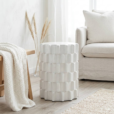 Off-white ceramic stool with raised block pattern styled in a living room setting
