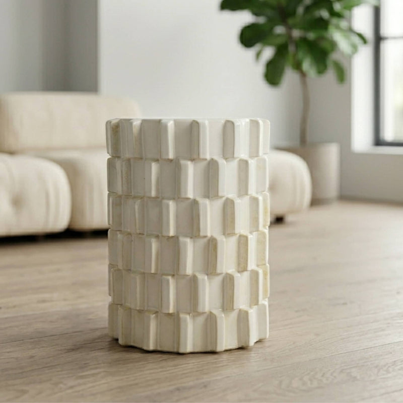 Off-white ceramic stool with raised block pattern styled in a living room setting
