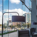 Modern interior with glass walls showing a cityscape, featuring a Modern black metal floor lamp with sleek design