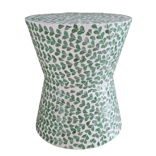 A round accent stool or side table with a white surface and green leaf pattern decor.