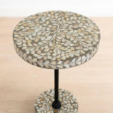 Round side table with a mother or pearl mosaic leaf pattern on the tabletop and matching circular base, supported by a black metal stand.