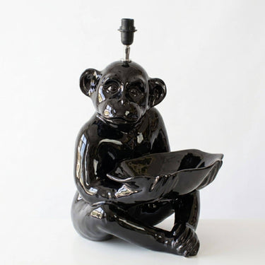 A glossy black ceramic monkey figurine lamp holding a matching bowl, photographed against a plain white background.