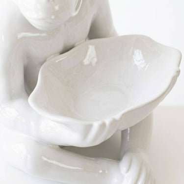 A glossy white ceramic bowl of a seated ceramic monkey lamp