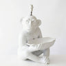 A glossy white ceramic table lamp shaped like a seated monkey holding a leaf, with a visible light socket at the top, photographed against a plain white background.