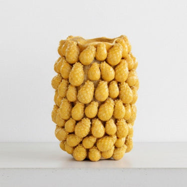 The yellow Ceramic Pineapple Vase styled as a standalone sculptural piece on a minimalist concrete table.