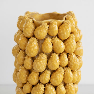 Detailed close-up of the tactile, raised pineapple-inspired texture on the surface of the yellow ceramic vase.