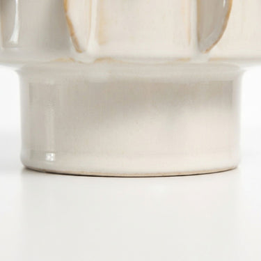 Close-up of a ceramic pot with a glossy off-white glaze pedestal base.