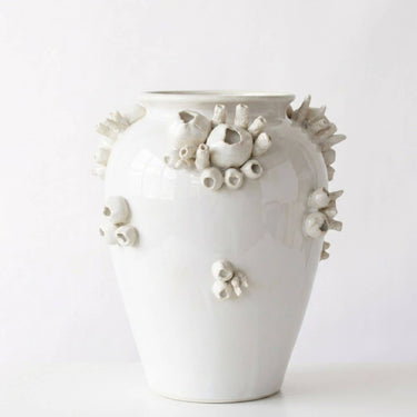 A glossy white ceramic vase decorated with raised, organic coral-like sculptural details in off-white and light gray, photographed against a clean white studio background.