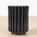A dark blue fluted ceramic side table with a glossy reactive glaze finish.