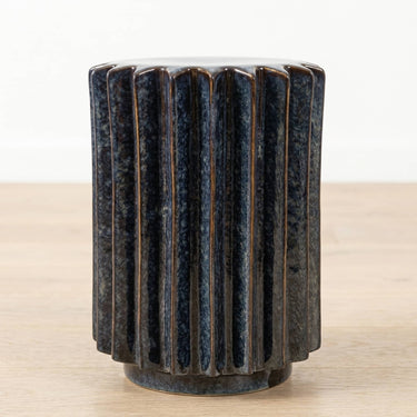 A dark blue fluted ceramic side table with a glossy reactive glaze finish.