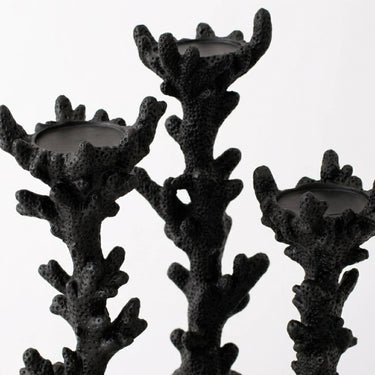 Three black coral-shaped candle holders with textured, branching stems and circular cup-like tops, shown against a plain light gray background.