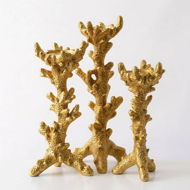 Three gold coral-shaped candle holders arranged together on a plain white background.
