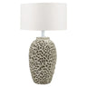 A modern table lamp with a cylindrical beige stone base, and a large white drum shade.