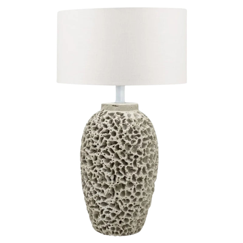 A modern table lamp with a cylindrical beige stone base, and a large white drum shade.