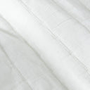 A close-up of white quilt bedspread with a stitched diagonal paneling.