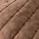 Close-up of a quilted fabric in a warm taupe-brown colour, showing stitched channel quilting.