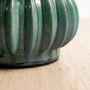 Close-up of a ribbed curvit accent table in a jade green glaze.