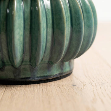 Close-up of a ribbed curvit accent table in a jade green glaze.