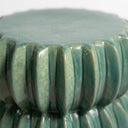 Close-up of a glossy jade ceramic accent table  a fluted, ribbed exterior and a flat circular top.