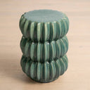 A small round ceramic side table with a glossy green glazed finish and a ribbed, flower-like segmented design.