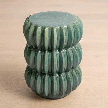 A small round ceramic side table with a glossy green glazed finish and a ribbed, flower-like segmented design.