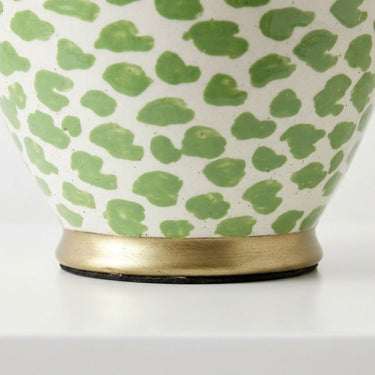 Close-up of a ceramic and green hand-painted spotted pattern, and a brushed gold metal base.