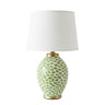 Table lamp with a white drum shade, a glossy white ceramic base covered in green spots, and gold-finished metal accents at the neck and base.
