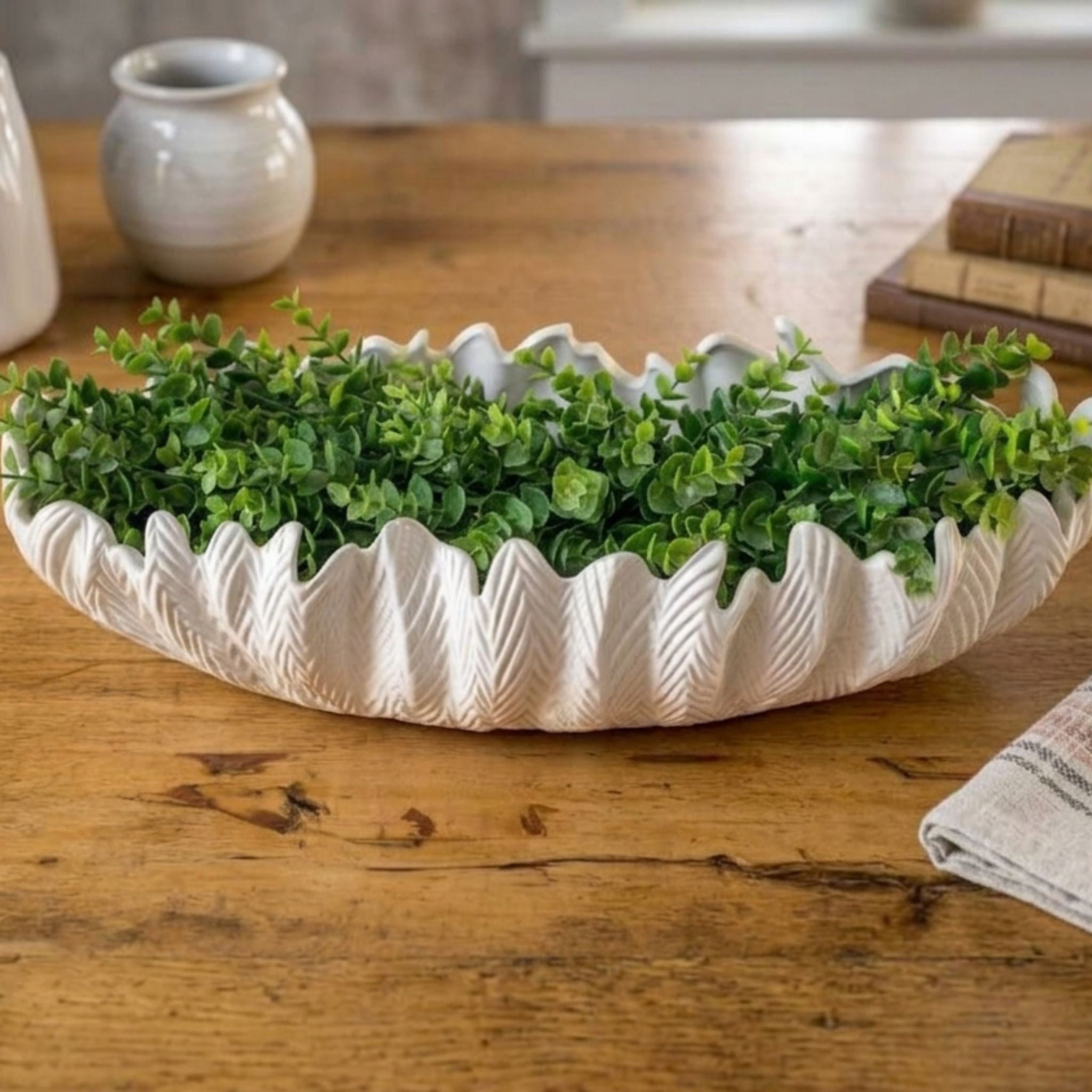 Délicat large white ceramic centrepiece bowl filled with lush green foliage, styled on a wooden table