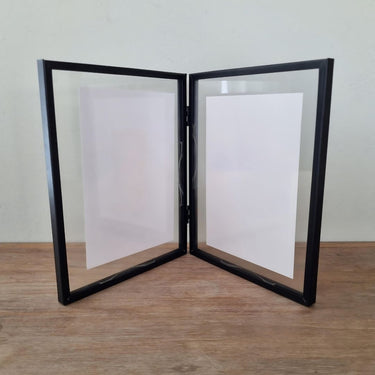 A double photo frame stand with black metal borders and clear glass panels, designed to display two photographs side by side.