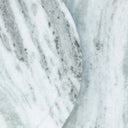 A close-up of a polished white marble surface with soft gray veining and a curved edge visible.