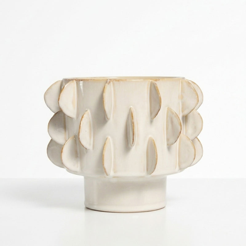 Eclipse sculptural flower plant pot with a textured pattern featuring a pedestal base in a warm ivory cream colour.
