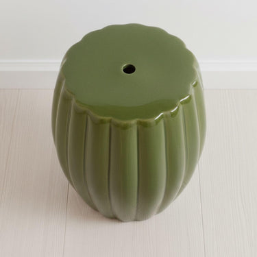 Top view of the green ceramic stool showing the central drainage hole and ribbed design.