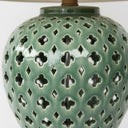 Detailed view of the intricate geometric cut-out pattern on a glossy emerald green glazed ceramic lamp base.