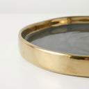 round tray with a polished gold-toned rim and a dark grey interior.