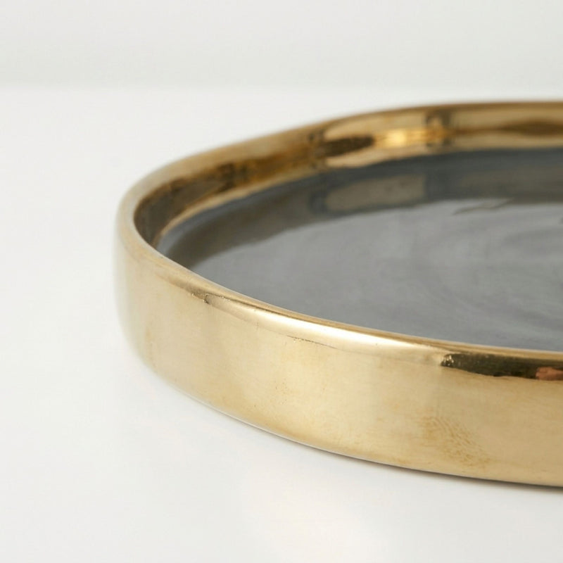 round tray with a polished gold-toned rim and a dark grey interior.