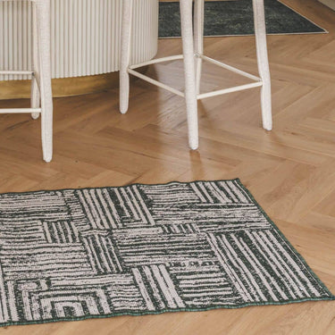 A rectangular gridlock runner rug with a dark green and off-white geometric pattern, in a kitchen setting.