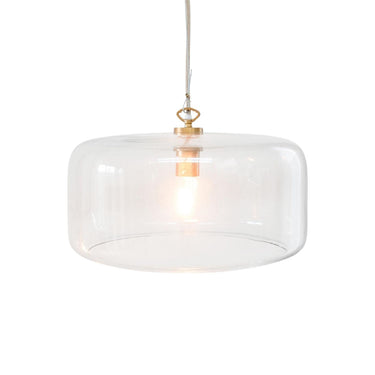 A modern pendant light with a clear glass drum shade and a brass metal fixture, suspended by a thin cord.