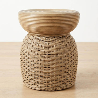 A natural woven rattan side table with a coiled circular round top and a cylindrical woven wicker base.