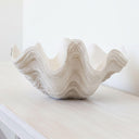 Side profile of a large decorative clam shell bowl displayed on a console table with a refined seaside aesthetic.