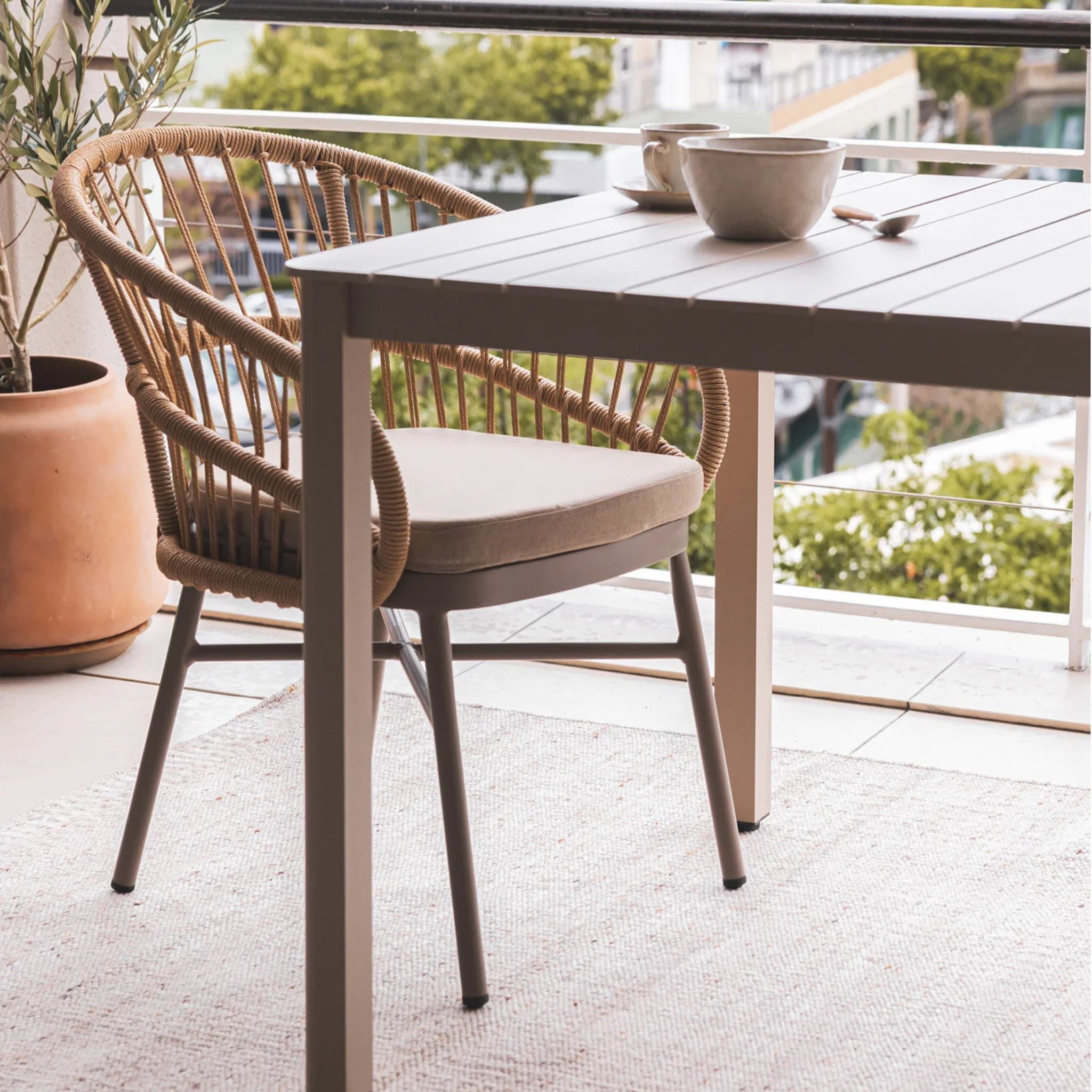 Lola Outdoor Dining Chair hand-woven rattan on a powder-coated aluminium frame with a cushion on patio.
