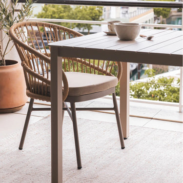 Lola Outdoor Dining Chair hand-woven rattan on a powder-coated aluminium frame with a cushion on patio.