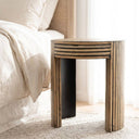 round accent table with graphic multidirectional natural wood stripe design and a curved arched block base.