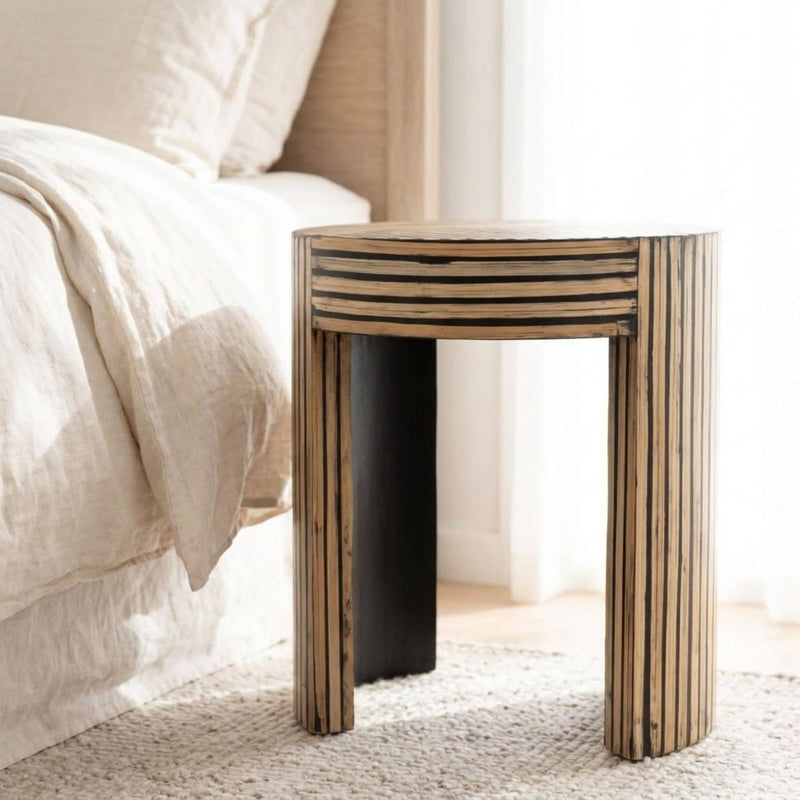 round accent table with graphic multidirectional natural wood stripe design and a curved arched block base.