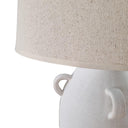 Close-up of a white ceramic lamp with a beige fabric shade on a white background