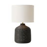 Cane table lamp with a textured dark black woven base and a cylindrical off-white fabric drum shade.