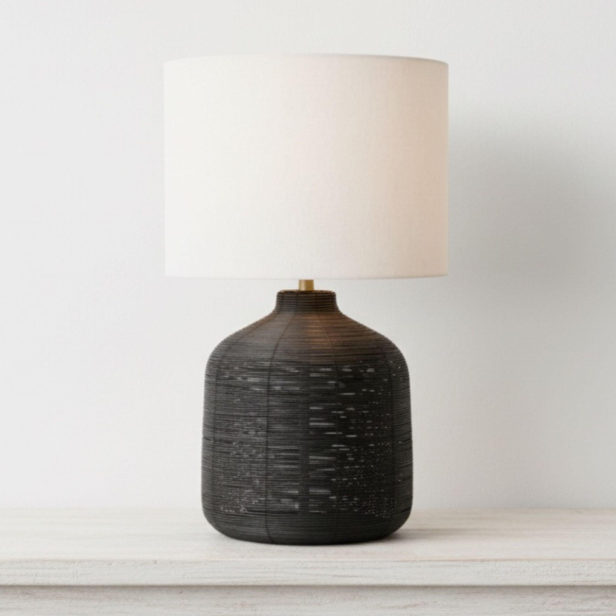 black woven rattan table lamp with a contemporary rounded base and contrasting neutral drum shade for modern organic decor.