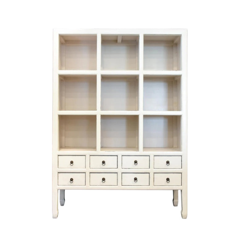 A tall, white  Mandarin-style display cabinet featuring nine open square cubby shelves above eight small drawers with brass ring pulls from Woodka Interiors