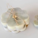 Set of four 11cm grey raw stone coasters with a scalloped flower edge and central brass inlay